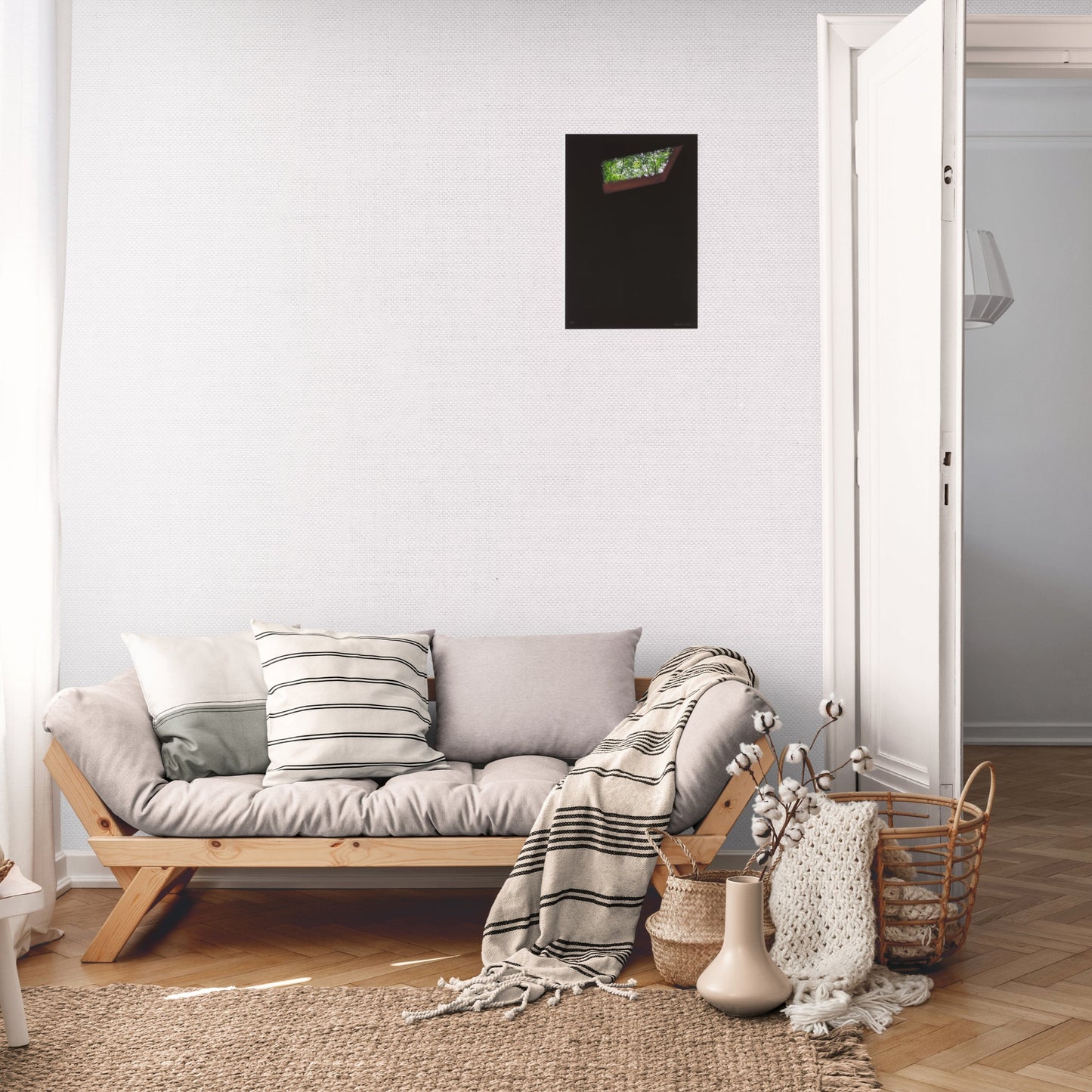 A lounge room with a grey sofa and cream blankets with an Alfredo Jaar print to scale hung on the wall.