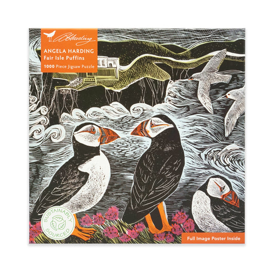 Jigsaw puzzle packaging with puffins and a scenic design with a lighthouse in the distance, featuring the brand 'Angela Harding'. The main colours are black, white, orange, purple and green.