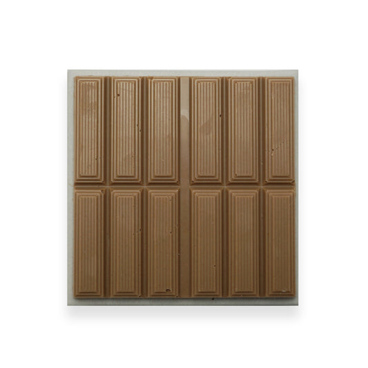 A square bar of milk chocolate sitting on a beige cardboard packet.