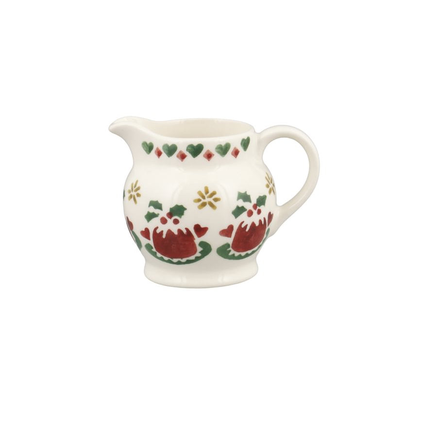 A small white ceramic creamer pitcher decorated with a festive Christmas pattern featuring red Christmas puddings, green holly leaves, and gold stars.