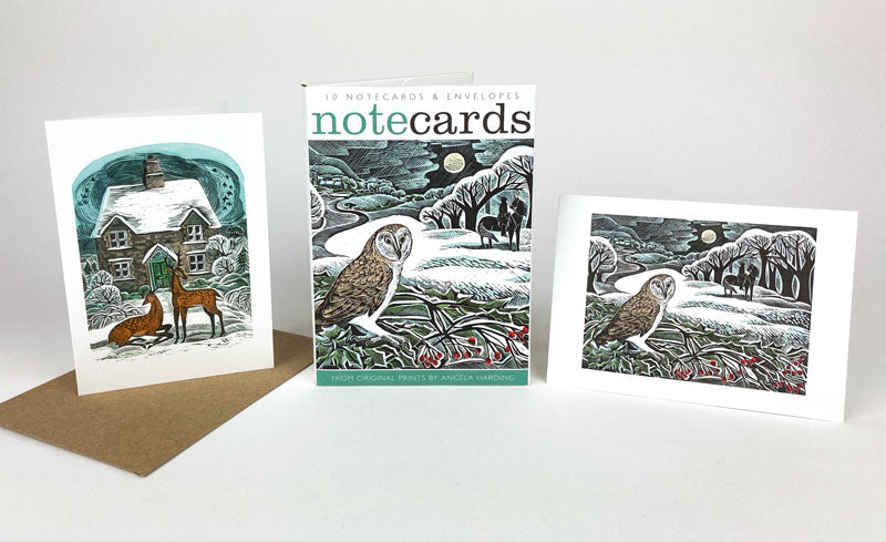 A pack of Christmas notecards featuring two original works by print maker Angela Harding. The vibes are festive, snowy and wintery with depictions of deer and an owl.