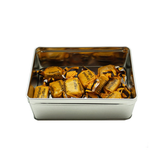 An open tin of individually wrapped clotted cream toffees.
