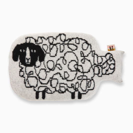 A grey wool hot water bottle that features a black knitted sheep pattern and a fabric Donna Wilson tag.