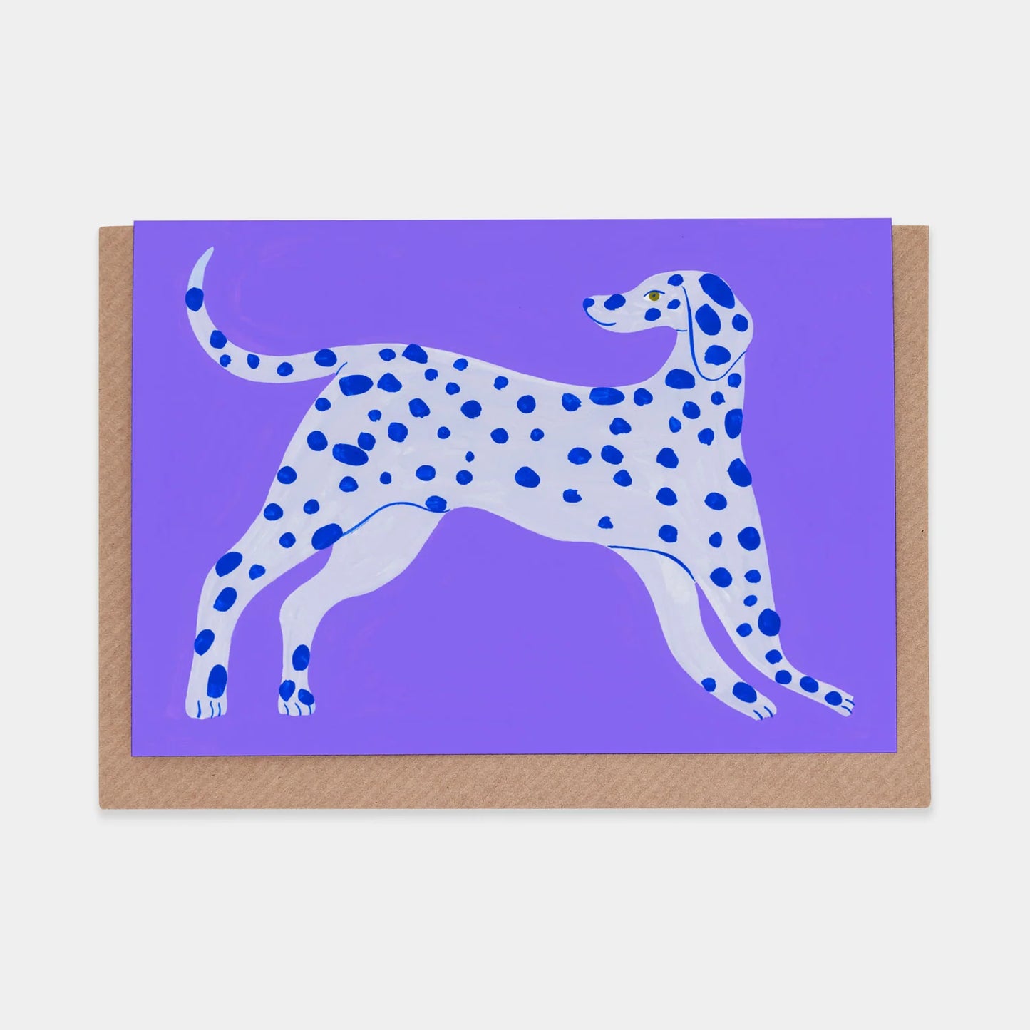 A vibrant illustration of a spotted dog in shades of white and blue, set against a purple background. The dog is depicted in a playful stance, showcasing its long legs and tail, with a friendly expression. The artwork is mounted on a brown card.