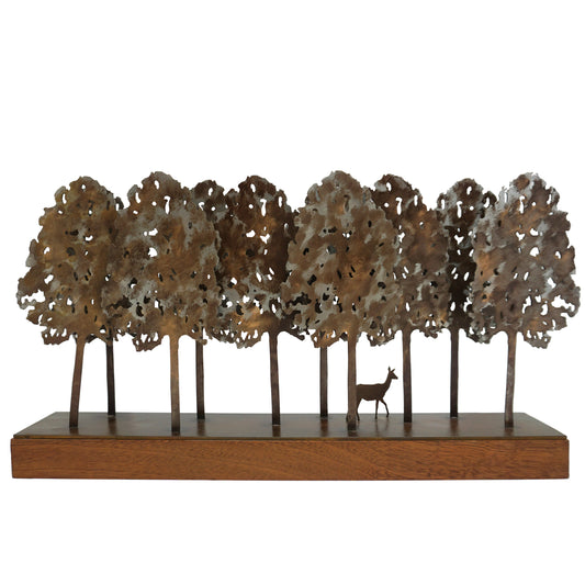Metal tree sculpture with a deer in the centre on a wooden base. The sculpture features ten trees that form a forest, and the canopies feature cut out holes.