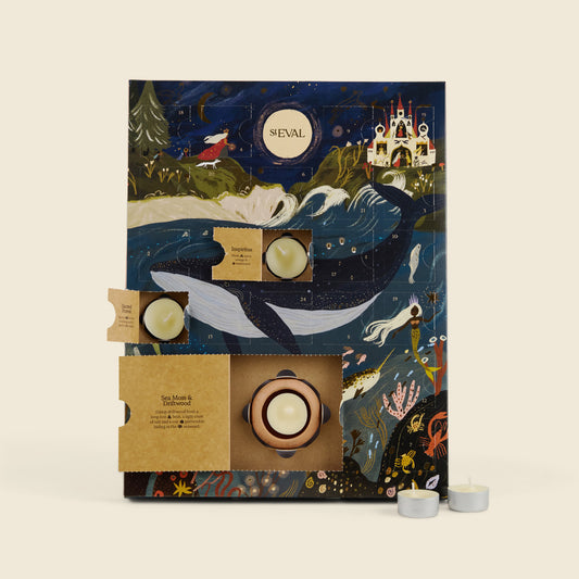 A St Eval brand tea advent calendar with an illustrated ocean scene featuring a whale, moon, castle, and sea creatures. The calendar is shown open with several tea items and tea light candles visible, set against a plain beige background.