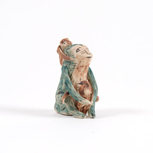 Small ceramic monkey whistle on a white background. The monkey is green in colour with two smaller monkeys on it's front and back.