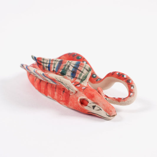 A pink, orange and blue ceramic whistle in the shape of an asp on a plain white background.