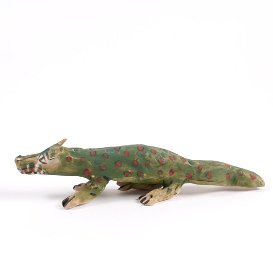 A painted ceramic crocodile whistle in shades of green and brown on a plain white background.