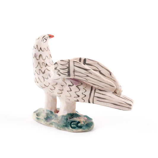 A painted dove ceramic whistle in shades of white and grey with an orange beak on a plain white background.