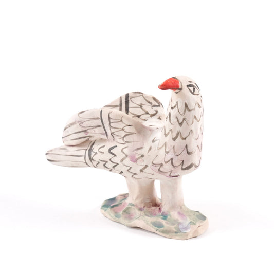A painted dove ceramic whistle in shades of white and grey with an orange beak on a plain white background.