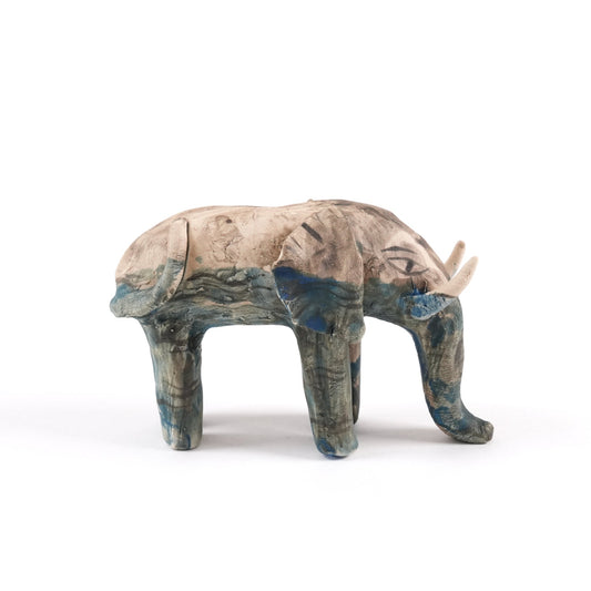 A painted ceramic elephant whistle with a ceramic painted calf. Both are in shades of beige, grey and blue and are standing on a plain white background.