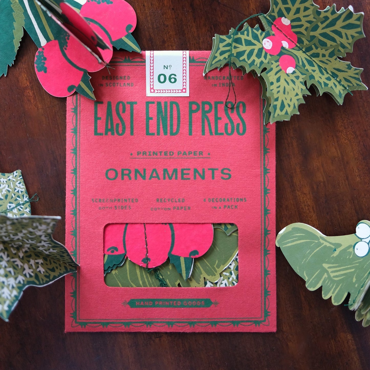 Pack of East End Press ornaments with decorative paper cutouts on a wooden surface