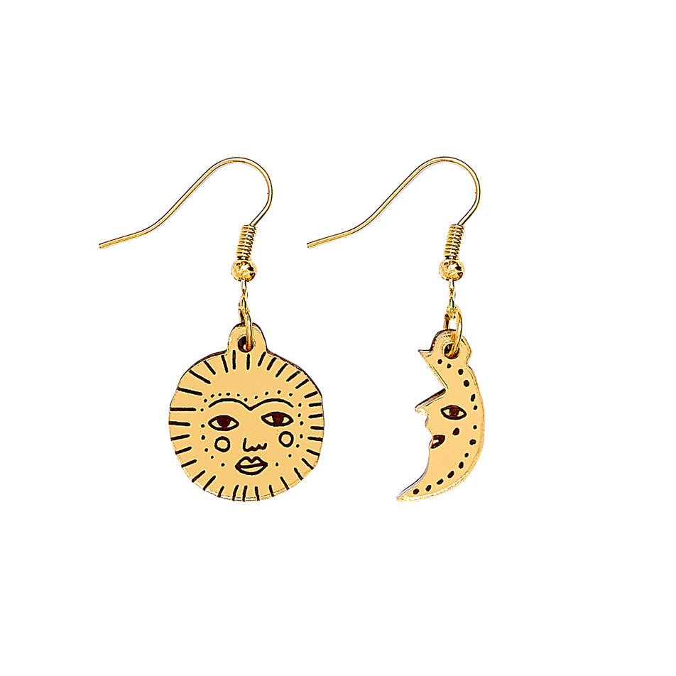 Gold sun and moon earrings on a white background