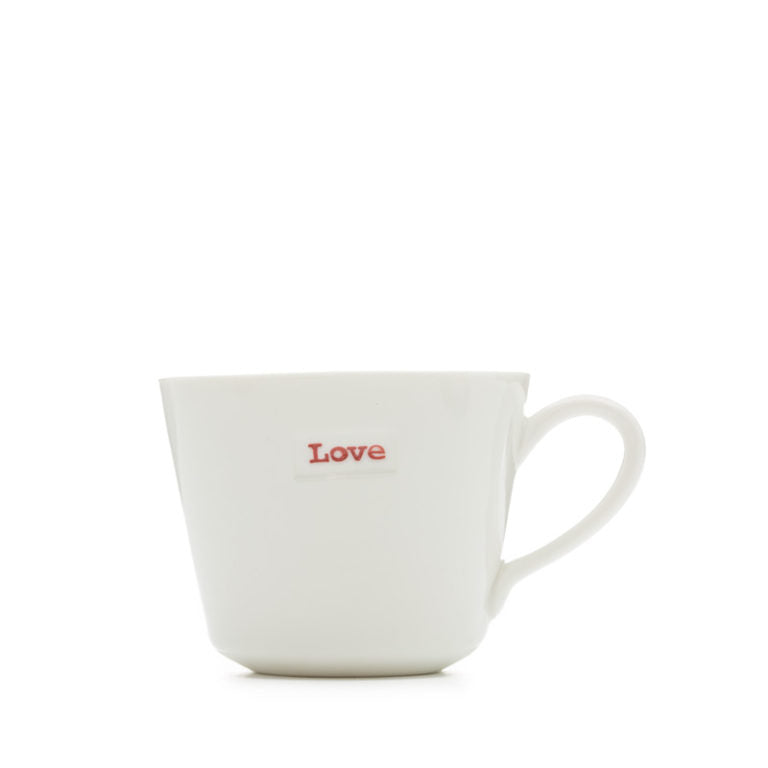 A white porcelain espresso cup with the word 'love' hand-stamped in red typewriter font on the side.