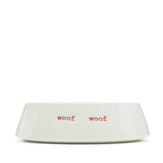 A white ceramic pet bowl with 'WOOF WOOF ' hand-stamped in red.