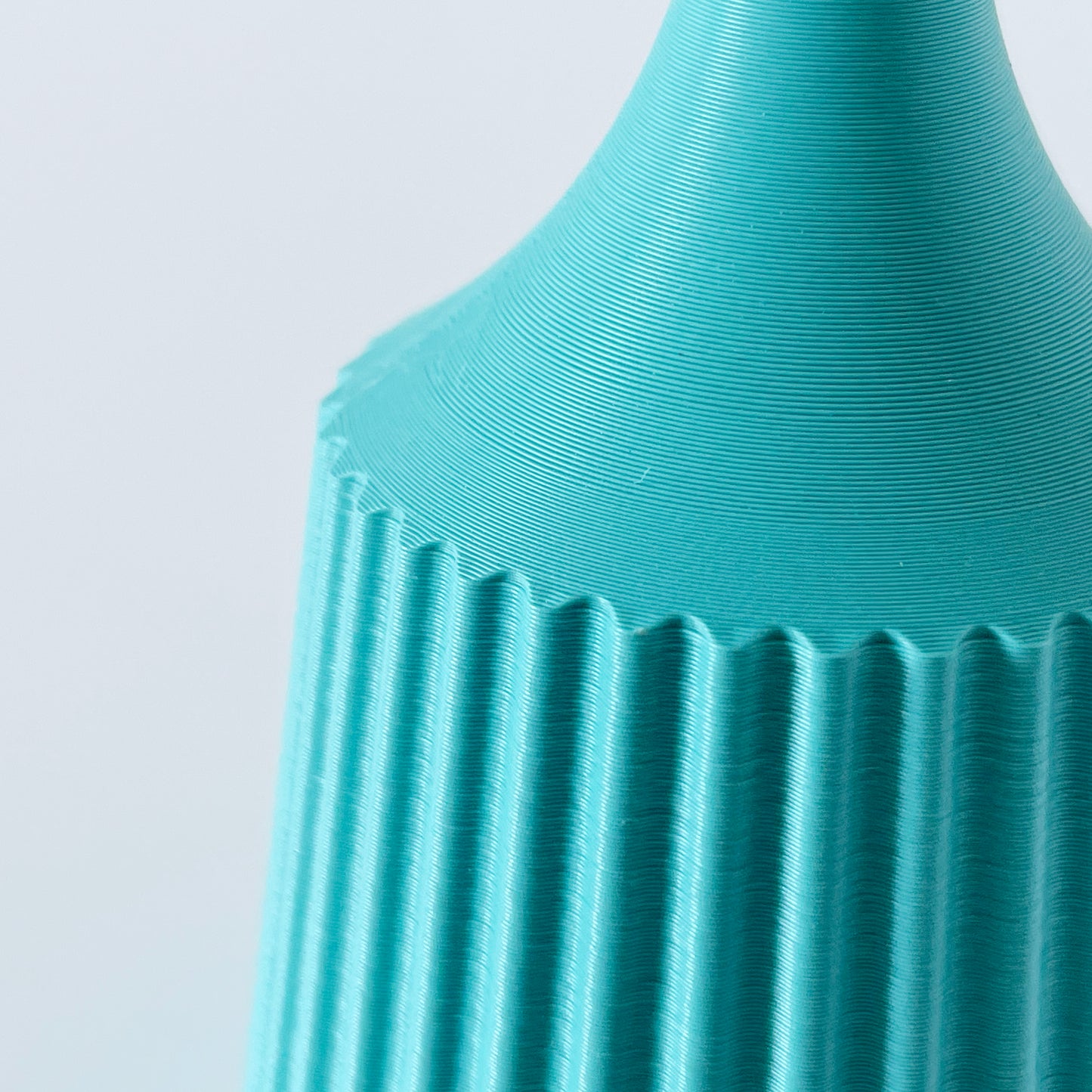 A close up showing the ribbed texture of a 3D printed turquoise vase.