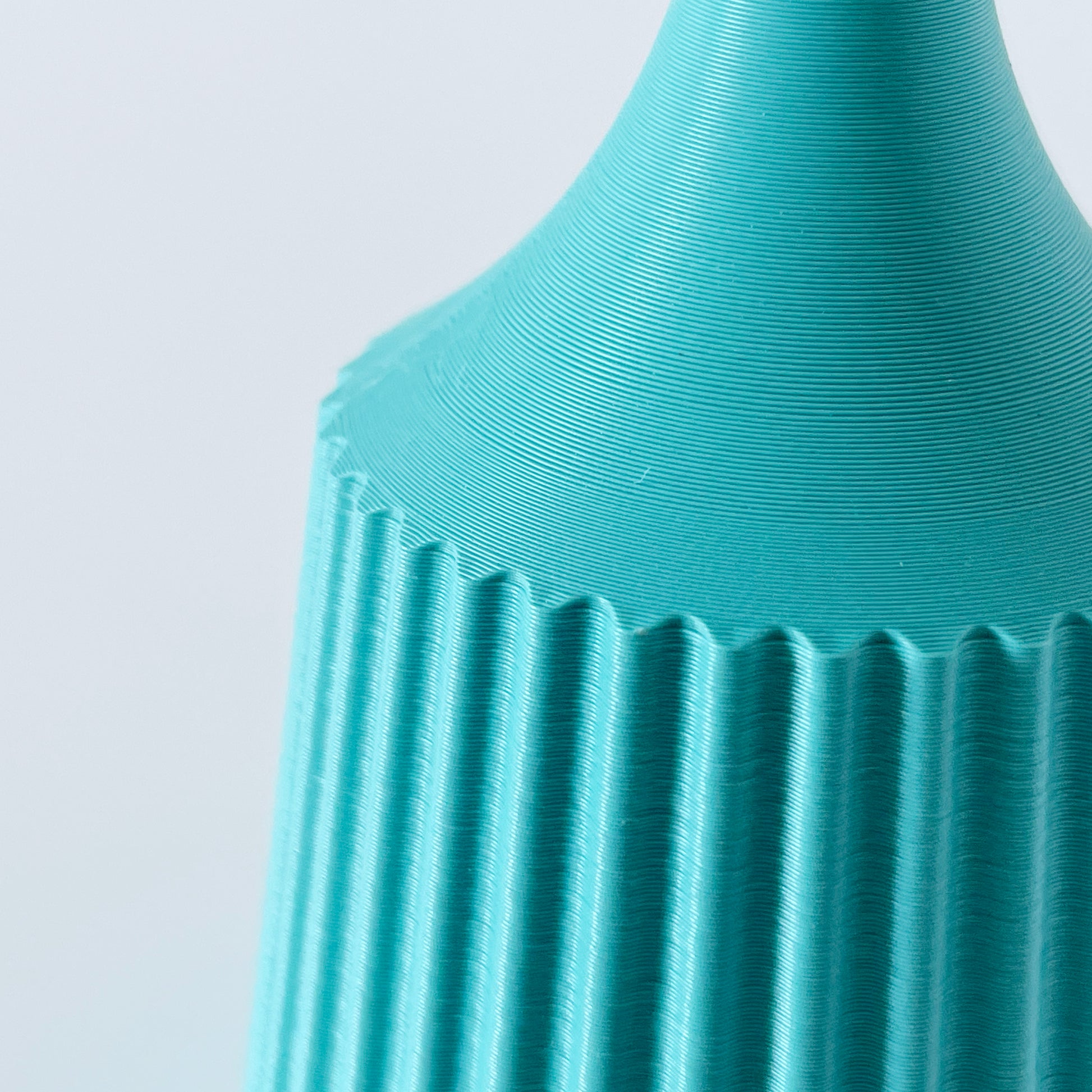 A close up showing the ribbed texture of a 3D printed turquoise vase.