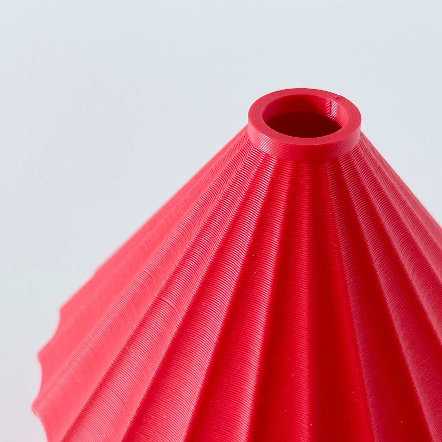 A close up of the opening on a 3D printed red triangular vase.