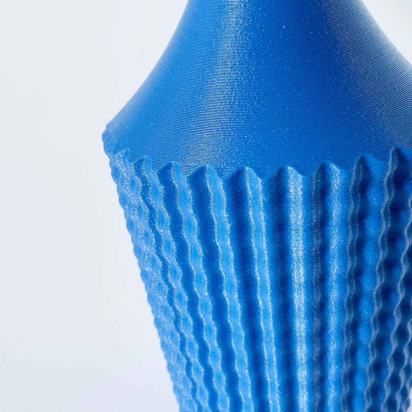 A close up shot showing the ribbed texture of a 3D printed blue vase.