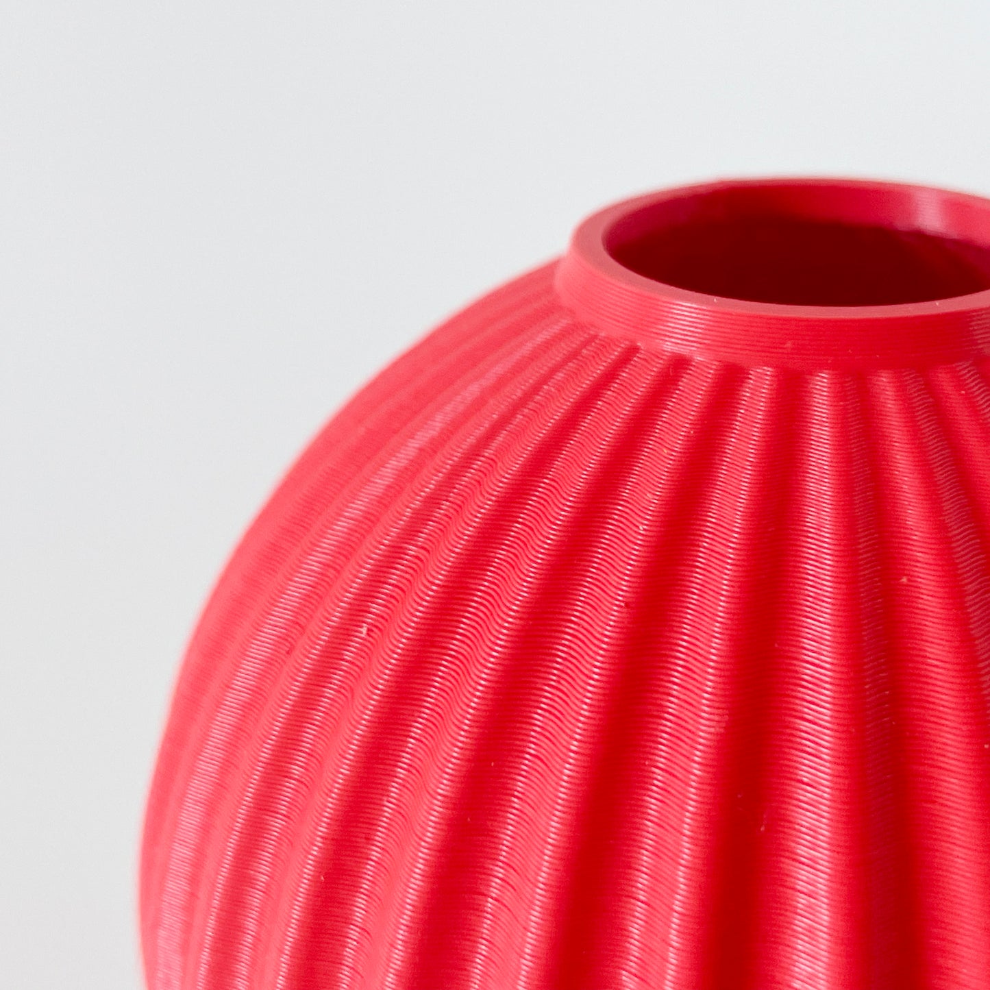 A close up of the opening on a 3D printed red spherical vase.