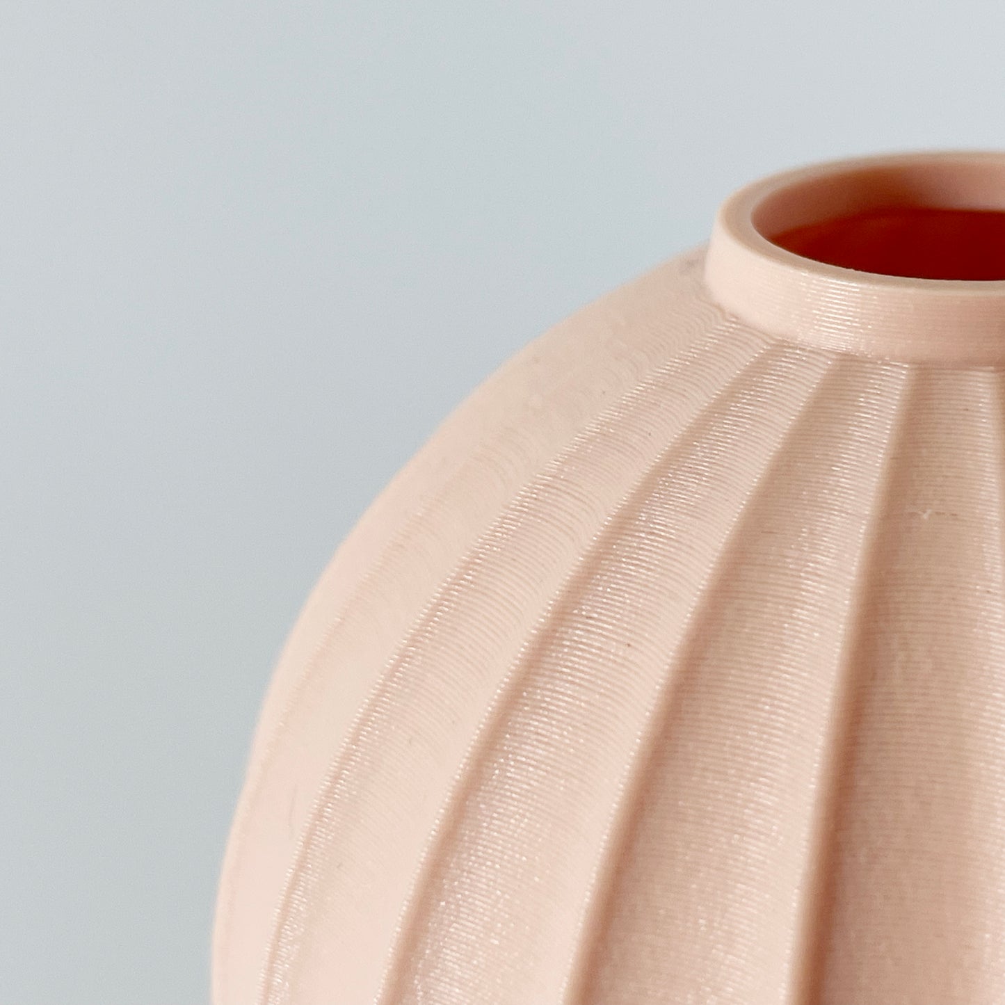 A close up showing a circular opening a the wavy pattern on a 3D printed vase.
