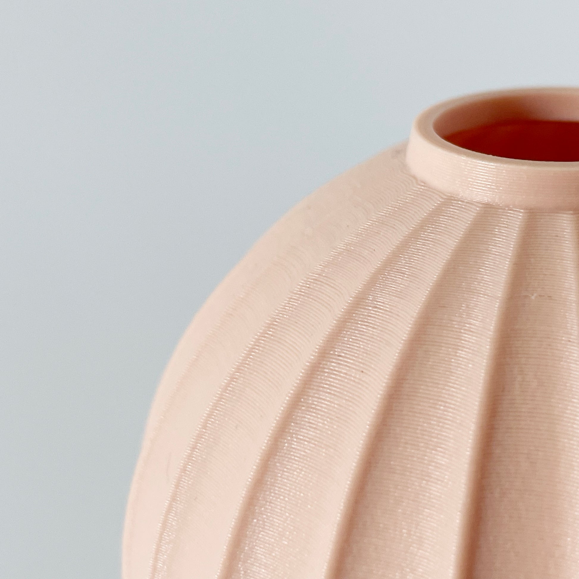 A close up showing a circular opening a the wavy pattern on a 3D printed vase.
