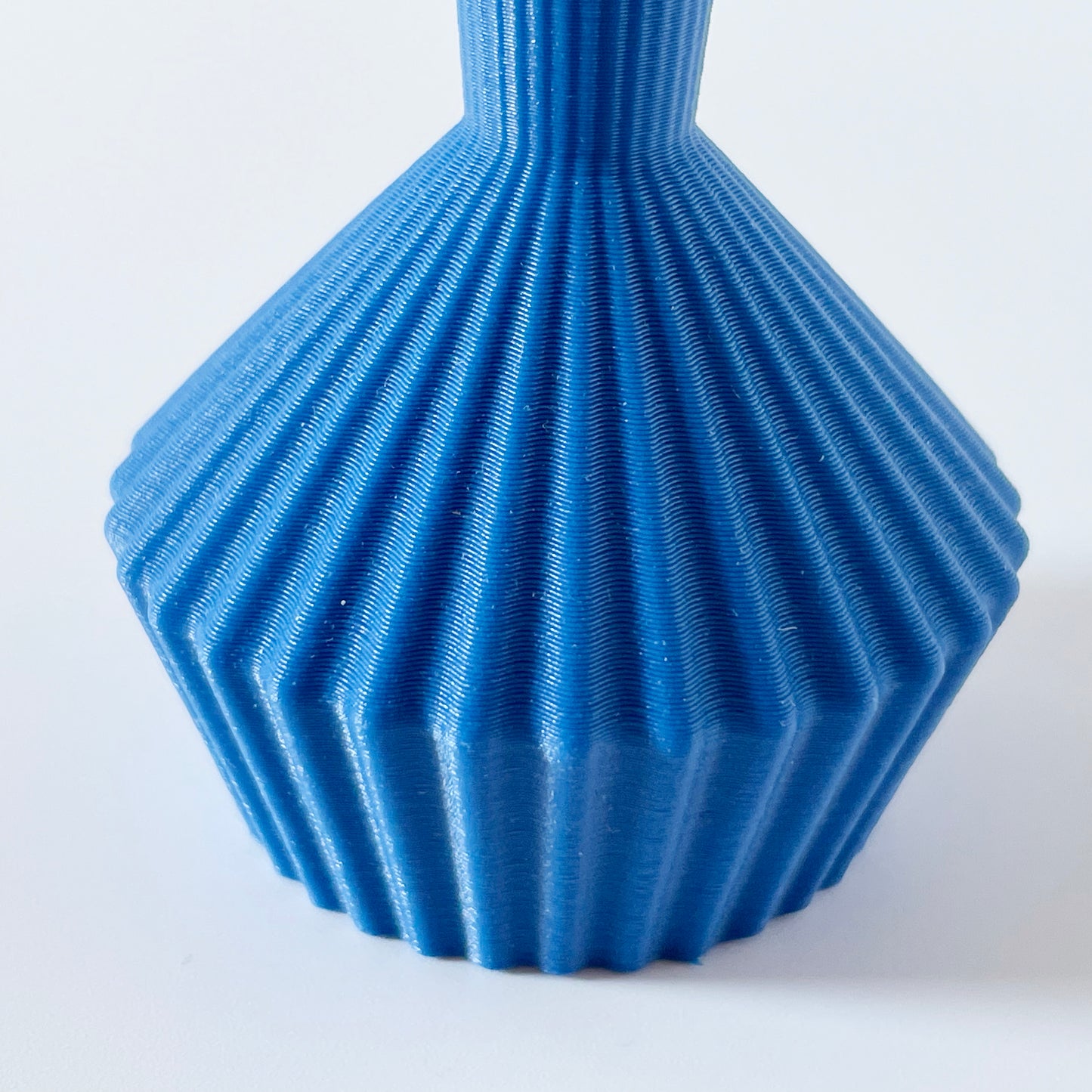 A close up shot showing the ribbed texture of a 3D printed blue vase.