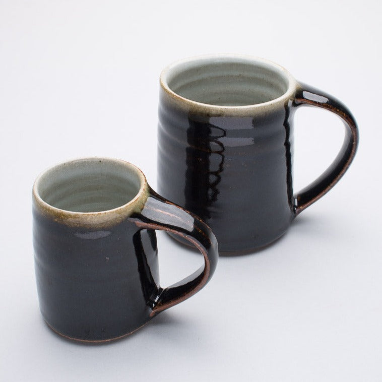 Two ceramic mugs with a speckled brown and black finish, one larger and one smaller, both with handles.