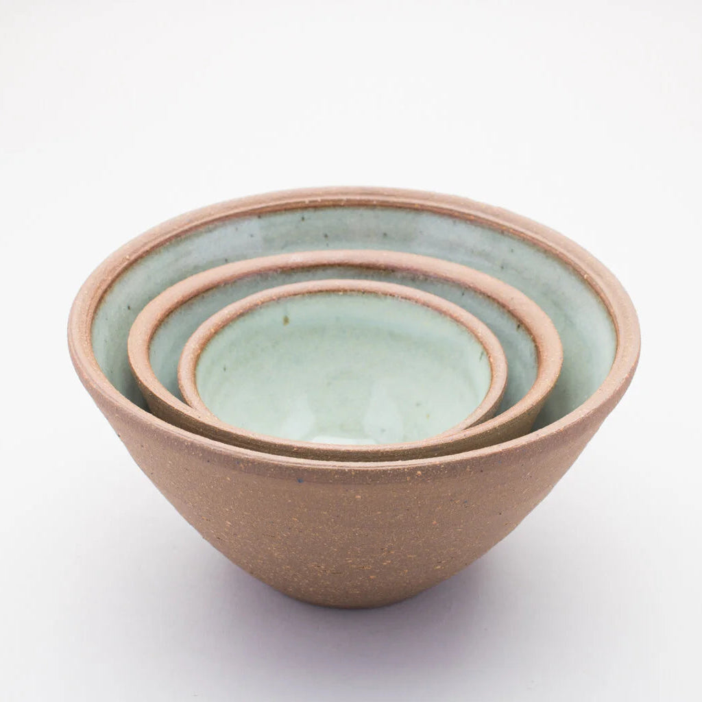 Set of three ceramic bowls stacked inside of each other with a green colour on the inside and a brown outer on a white background