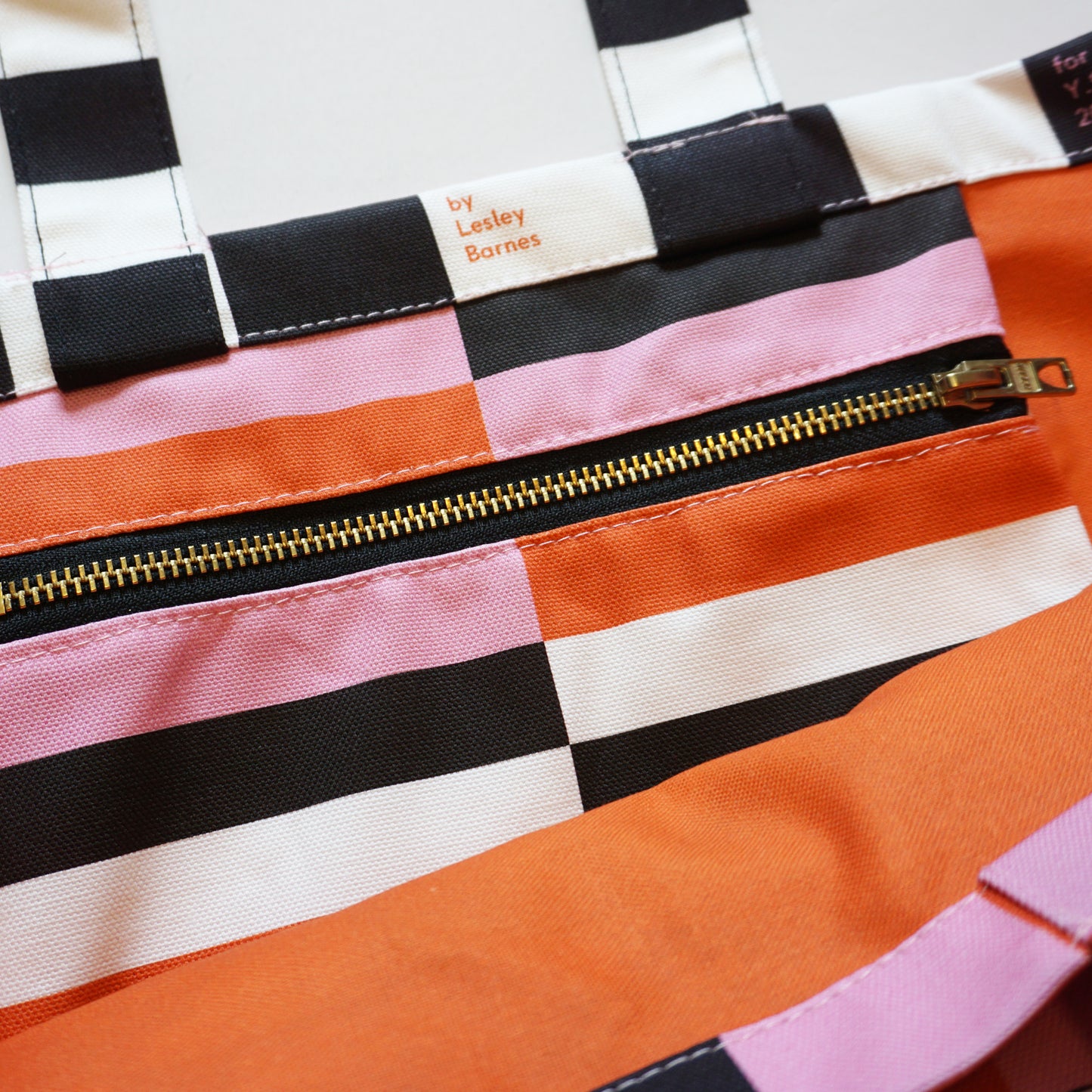 Colorful striped bag with a gold zipper and visible brand name.