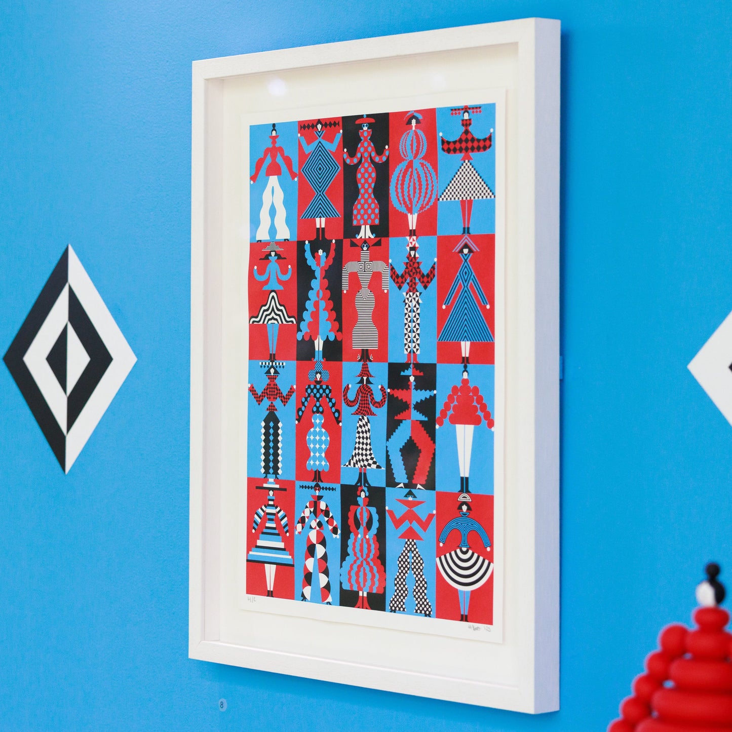 Framed artwork with geometric patterns on a blue wall with decorative elements.