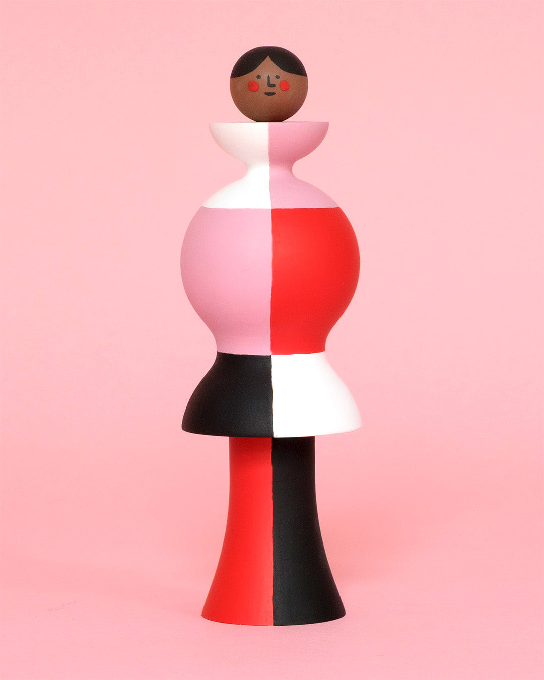 A colourful sculpture with a white, red, black and pink stripey body with red and black legs on a plain pink background.