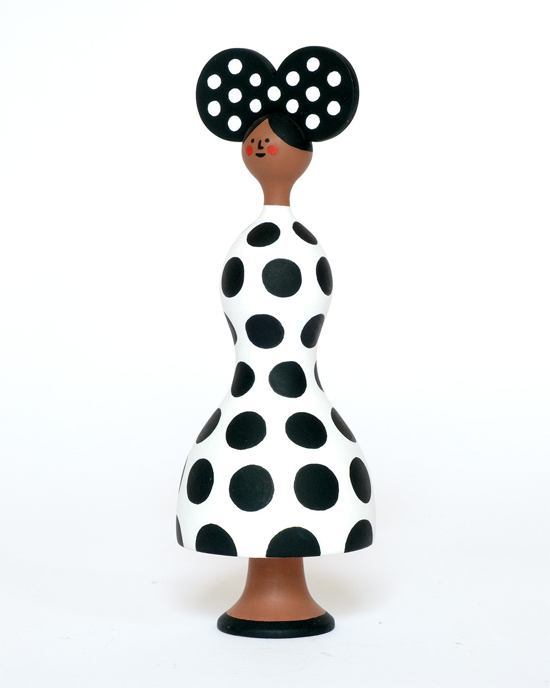 A monochrome sculpture with a black and white spotty body with a matching headdress on a plain white background.