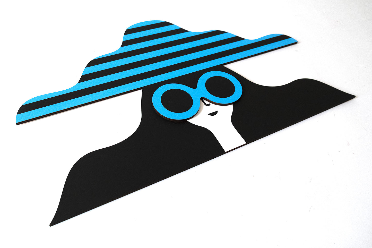 A wooden painted face featuring a stripey blue and black hat and a pair of blue sunglasses with long black hair.