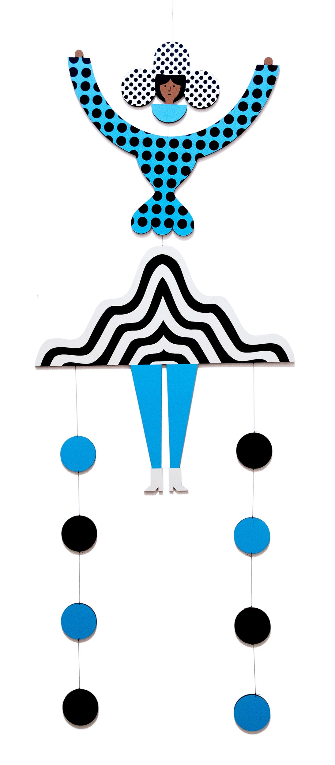 A hanging wooden colourful mobile featuring a full figure with a headdress and boots covered in bright geometric patterns.