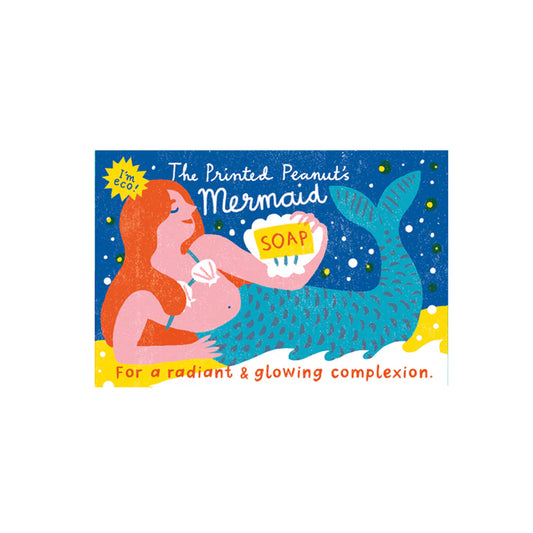 A vibrant illustration of a mermaid holding a bar of soap, set against a starry background. The packaging features playful text promoting the soap for a radiant and glowing complexion.