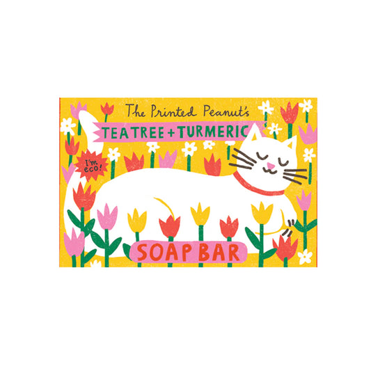 A vibrant soap bar packaging featuring a sleeping white cat surrounded by colourful flowers. The label reads "The Printed Peanut's Tea Tree + Turmeric Soap Bar" with a playful design and eco-friendly message.