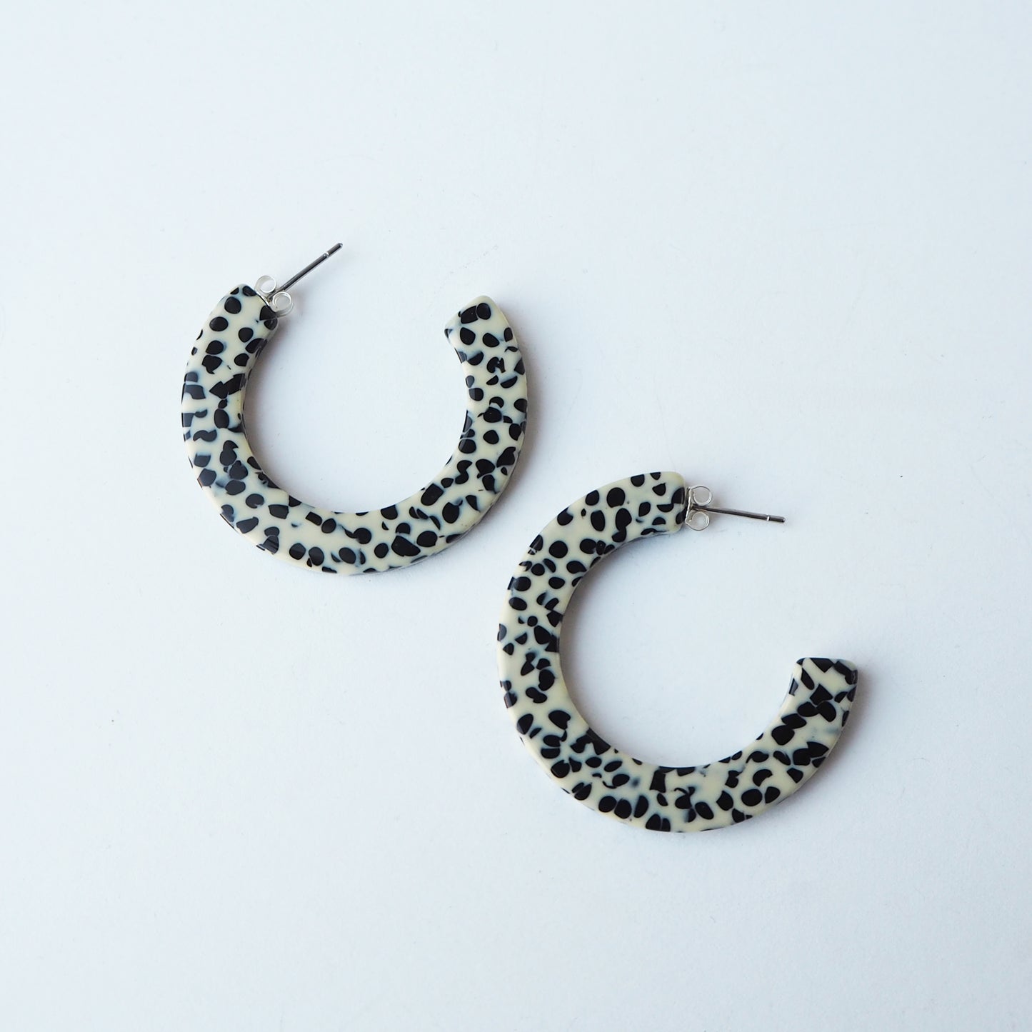 Pair of hoop earrings with a black and white dalmatian pattern on a light grey background