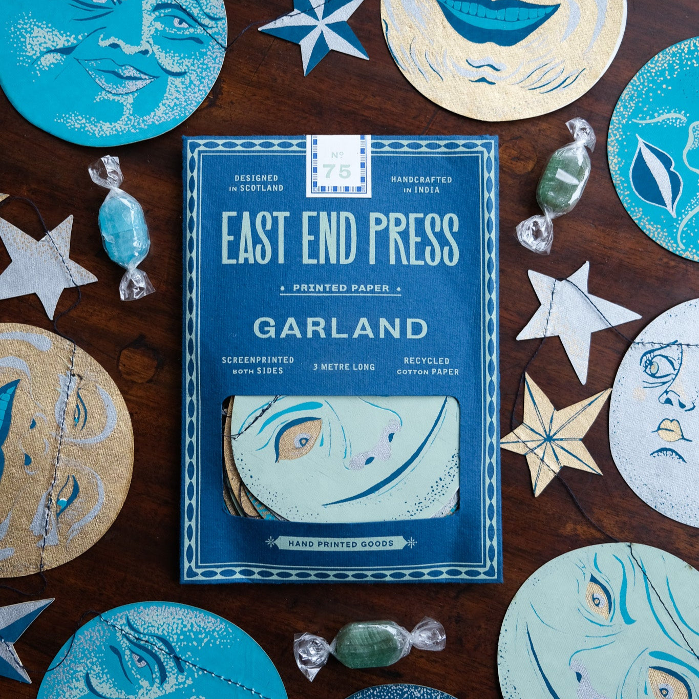 Pack of East End Press Garland with decorative paper cutouts on a wooden surface