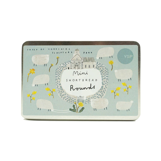 A rectangular metal tin of mini shortbread rounds with a blue label that features illustrated sheep and flowers.