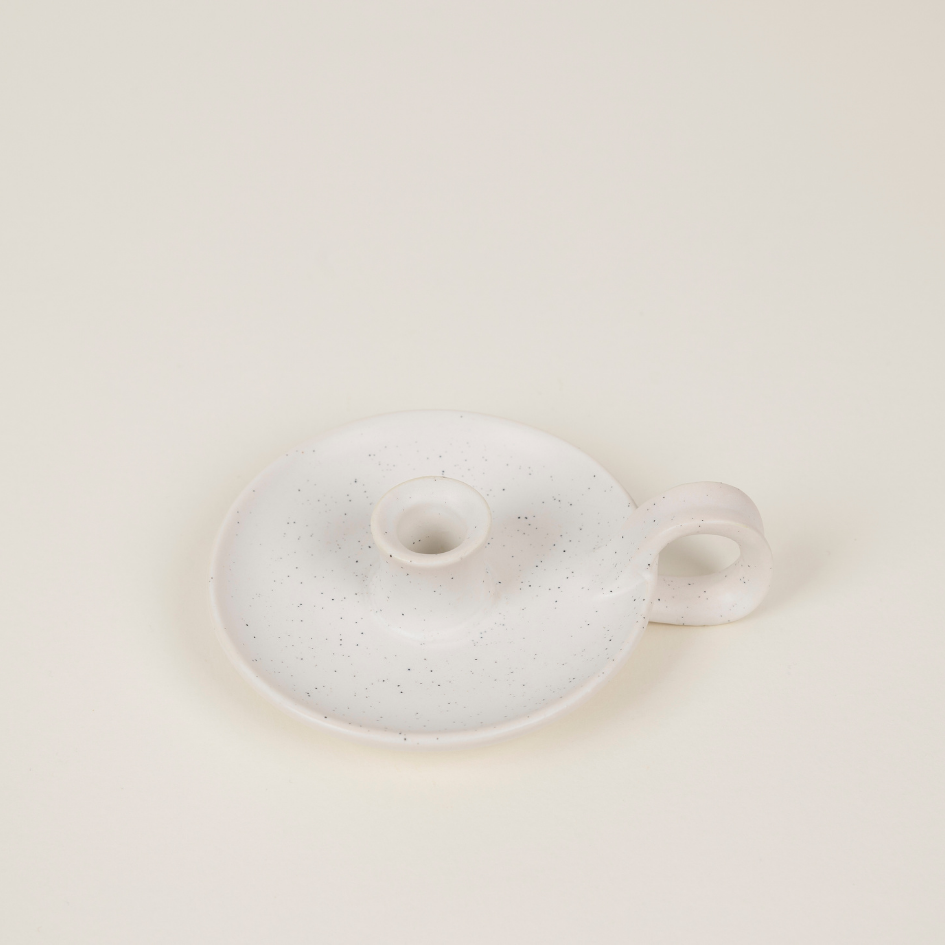 Speckled ceramic candle holder with a small handle on a light beige background