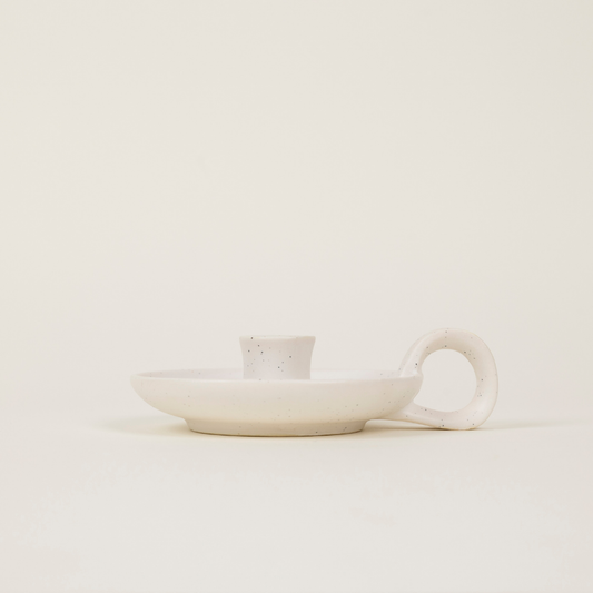 White ceramic dish with handle on a light beige background