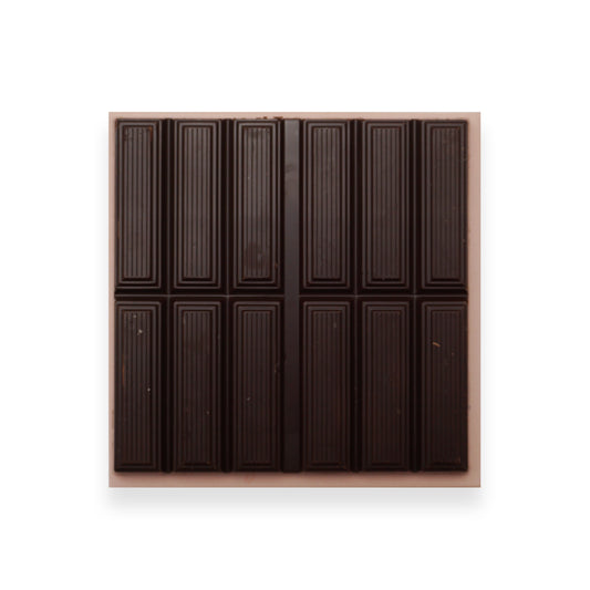 An open bar of dark chocolate sitting on an orange cardboard packet.