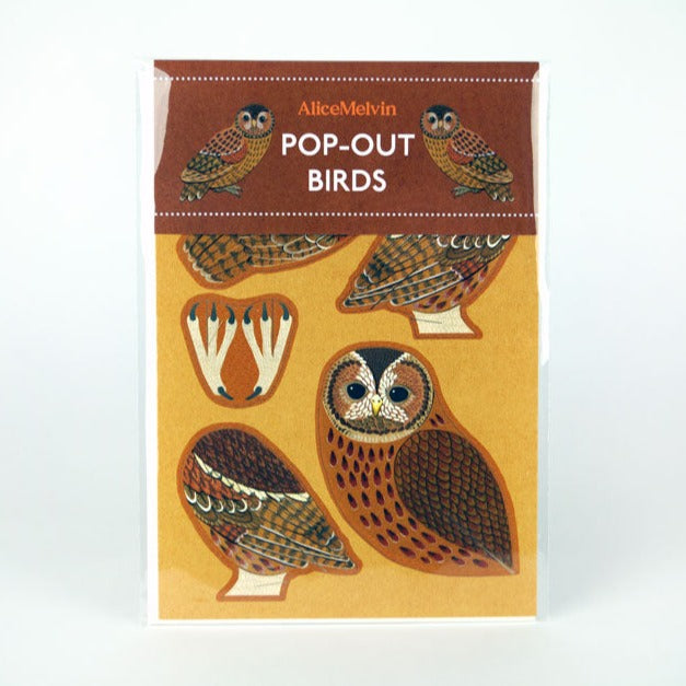 A pack of pop-out bird decorations featuring intricately designed owls. The packaging is brown with the text "Alice Melvin Pop-Out Birds" at the top. The birds are displayed on a warm, golden background, showcasing their detailed patterns.