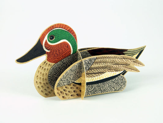 A decorative wooden duck model, featuring intricate patterns and vibrant colours. The duck has a green head, reddish-brown face, and detailed feather designs in shades of brown and cream, set against a plain white background.