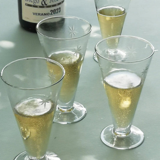 Four glasses of prosecco with a bottle labelled 'Diego & Jose Luis' on a reflective surface.