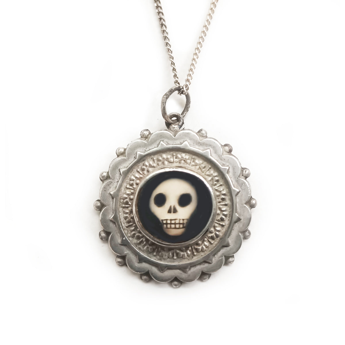 Antique looking medallion silver pendant with a hand painted black and white skull insert, attached to a sterling silver chain.
