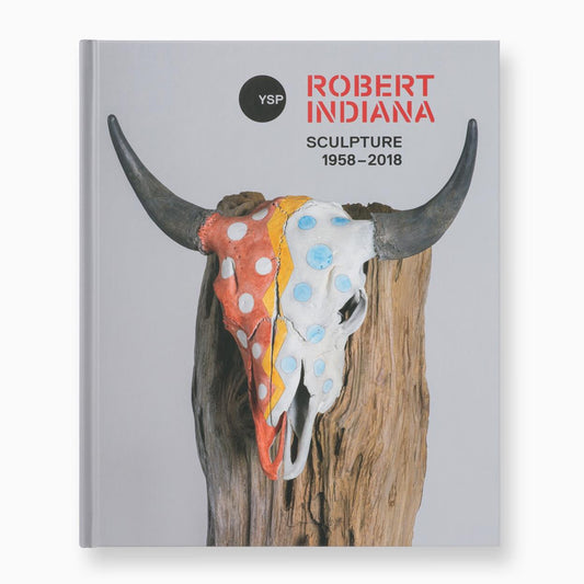 A book cover featuring a bull skull adorned with colourful paint splashes, set against a plain background. The title reads "Robert Indiana: Sculpture 1958–2018" in bold red letters, with a circular logo in the top left corner.