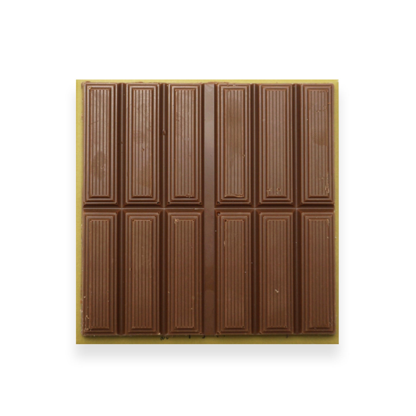 A square bar of milk chocolate sitting on a brown cardboard packet